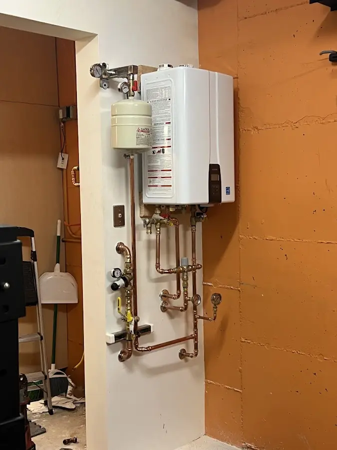 Plumbing technician inspecting water heater connections in Burrillville